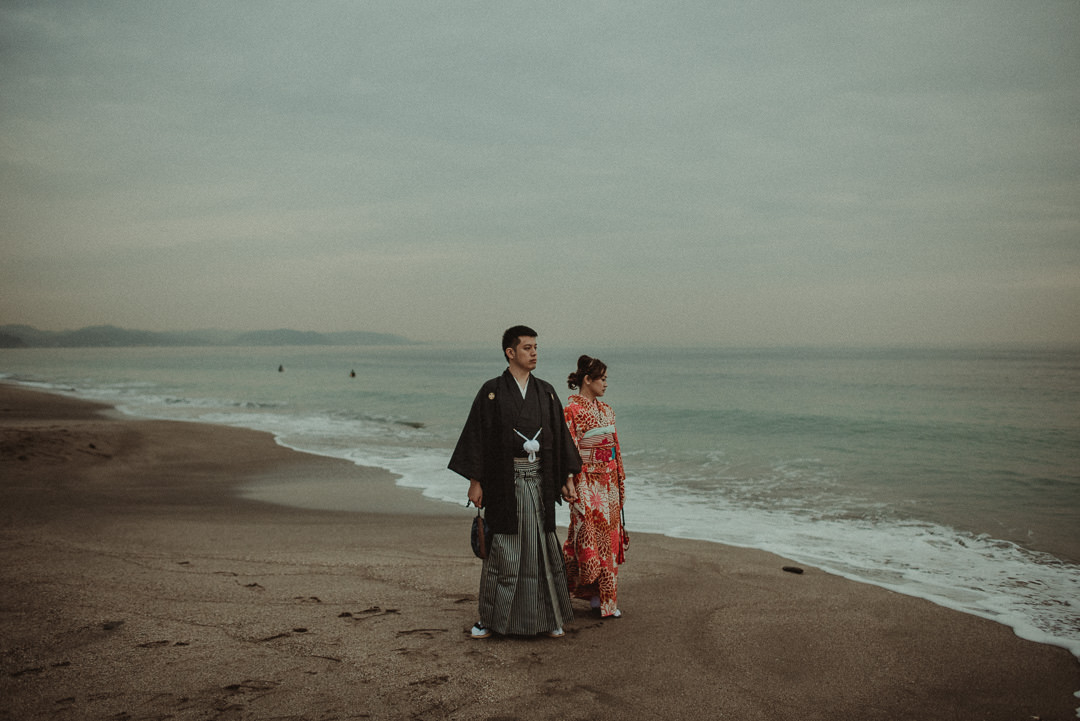 Couple who decided to elope in Japan on the Pacific ocean beach. They are wearing traditional Japanese clothes.