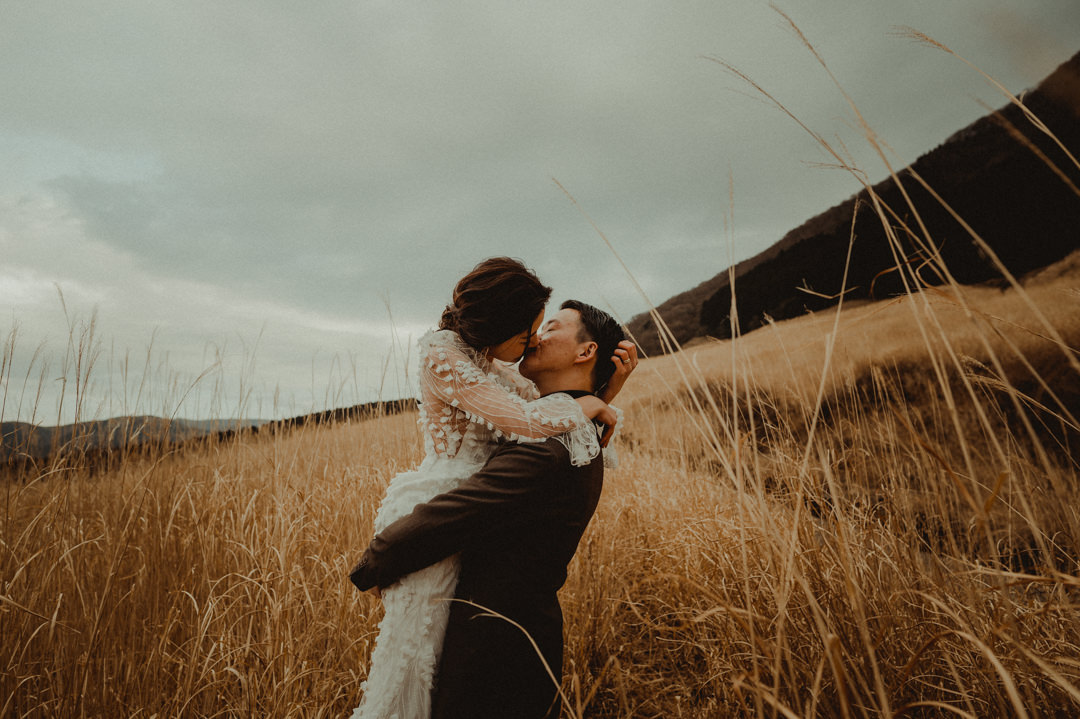 Couple who chose to elope in Japan kissing in the Japanese pampas grass fields.  