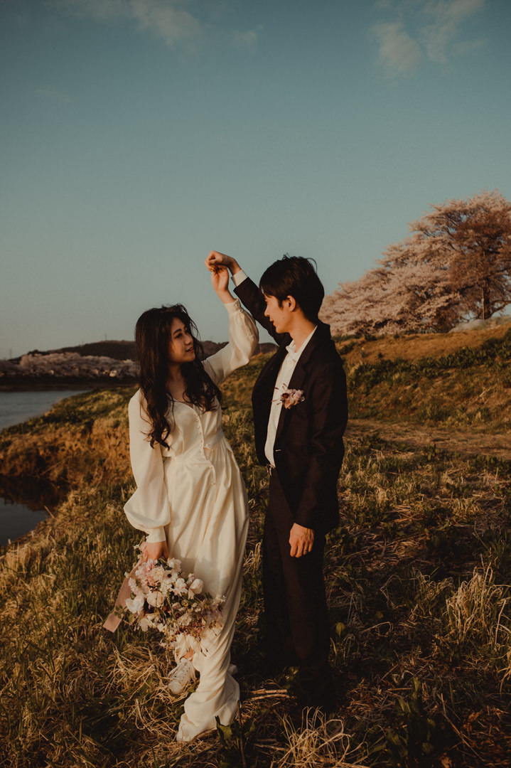 Dancing by the river surrounded by Japan cherry blossom trees
