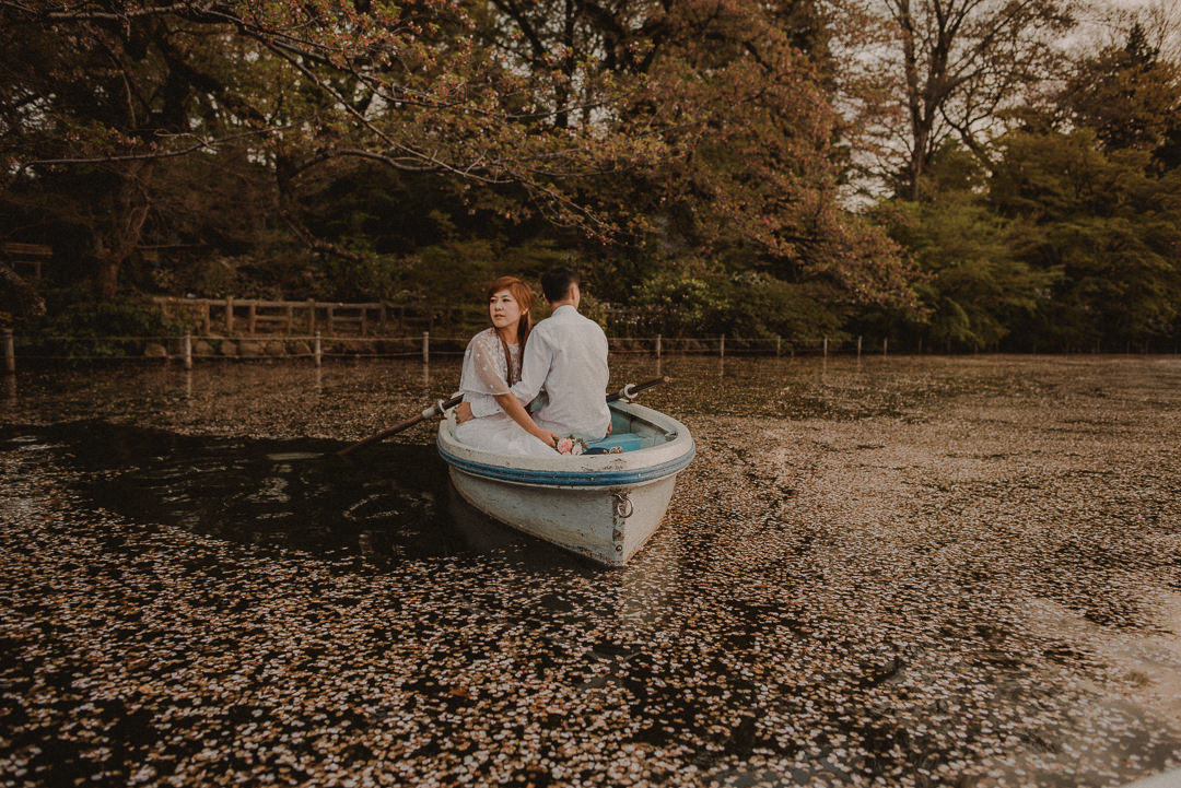 Petals making a flower carpet in the lake, couple in the boat
