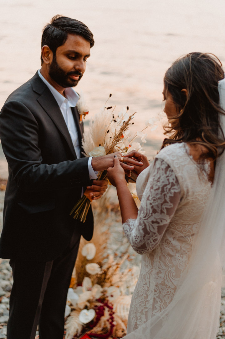 Bride putting a ring on grooms finger during wedding ceremony on their fall elopement in Japan