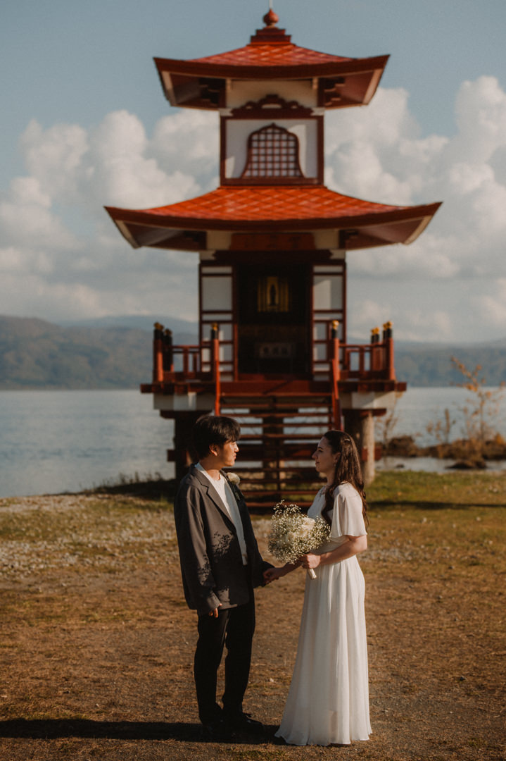 Hokkaido Elopement - The couple is looking each other in front of the pagoda 