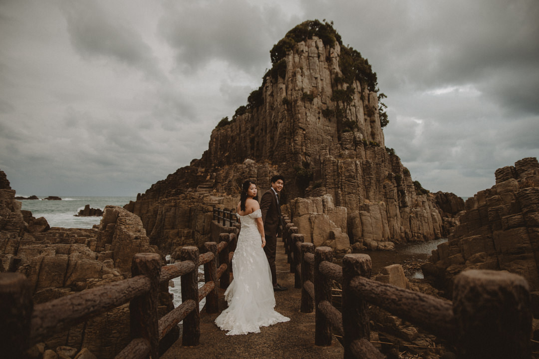 Japan Roadtrip Elopement - Couple standing in front of majestic rock formation