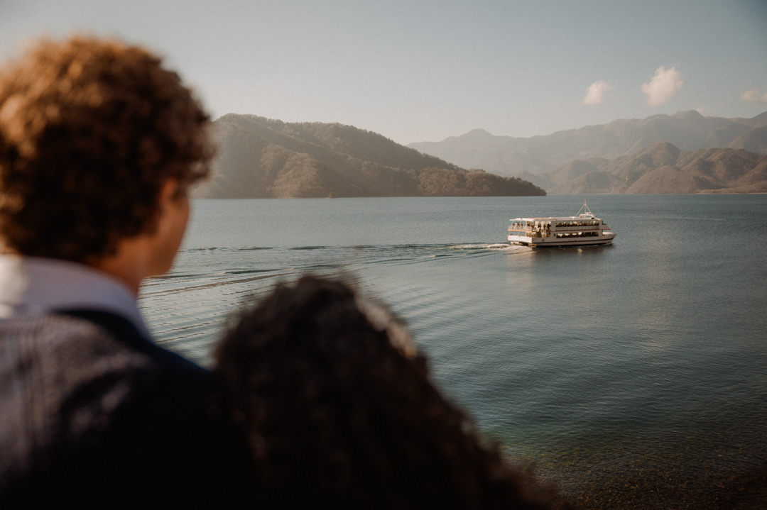 laid-back elopement in japan - couple watching a boat in the lake 
