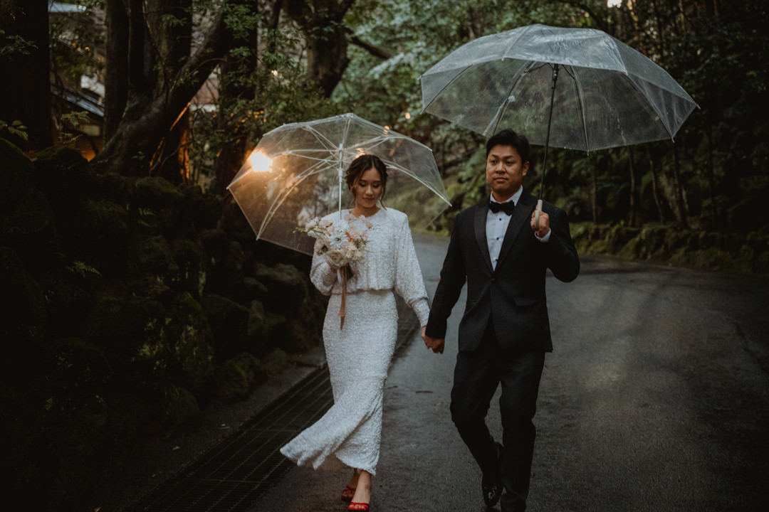Couple walks along the path, rainy day elopement in Japan 