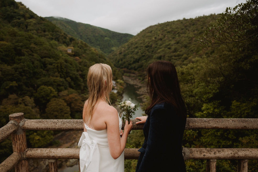 The couple takes a photo near the river, a same sex elopement in Japan.